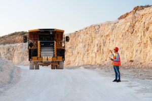 Foreman directing a dumper truck in a quarry using a tablet